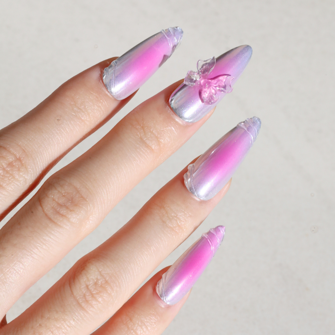 Angled photo of light skinned hand with Pink Aura Chrome Bow Nails