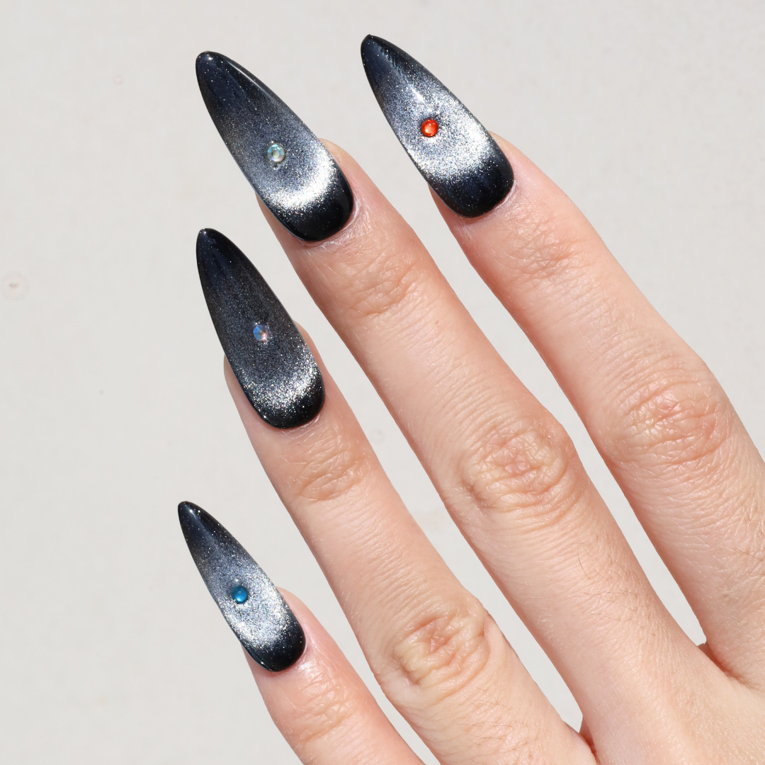 Angled photo of light skinned hand with Black Cateye Gem Nails