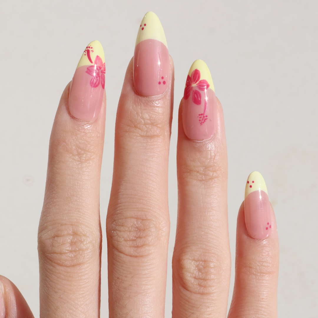 Light skinned hand with Pink Hibiscus Yellow French Tip Nails