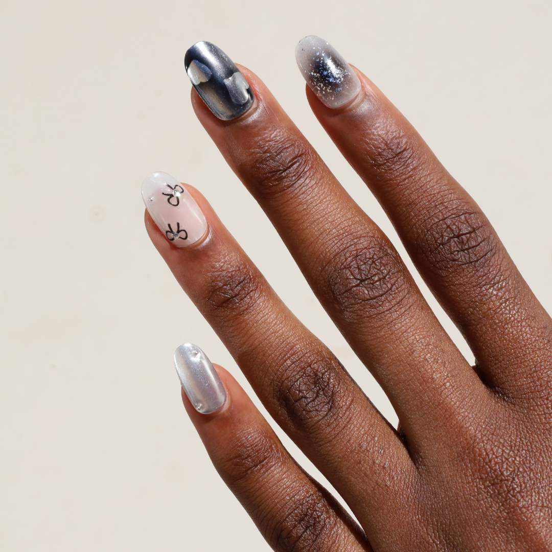 Angled photo of dark skinned hand with Silver Bow Chrome Nails